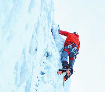 Climber in red jacket climbing an ice wall